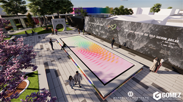 Aerial rendering of an outdoor memorial plaza featuring a long rectangular interactive surface with shifting rainbow colors. Visitors walk along wide stone pathways surrounded by trees, sculptures, and a large black wall engraved with text and artwork.